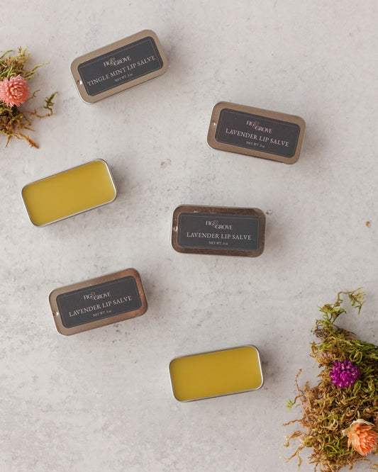 Collection of lip balm tins on a textured surface with floral elements -  Fig & Grove