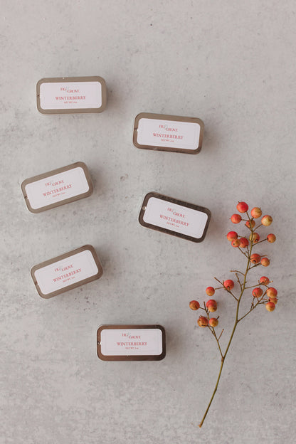Winterberry lip salve tins on neutral background with festive red berries - Fig & Grove cranberry and lime scent